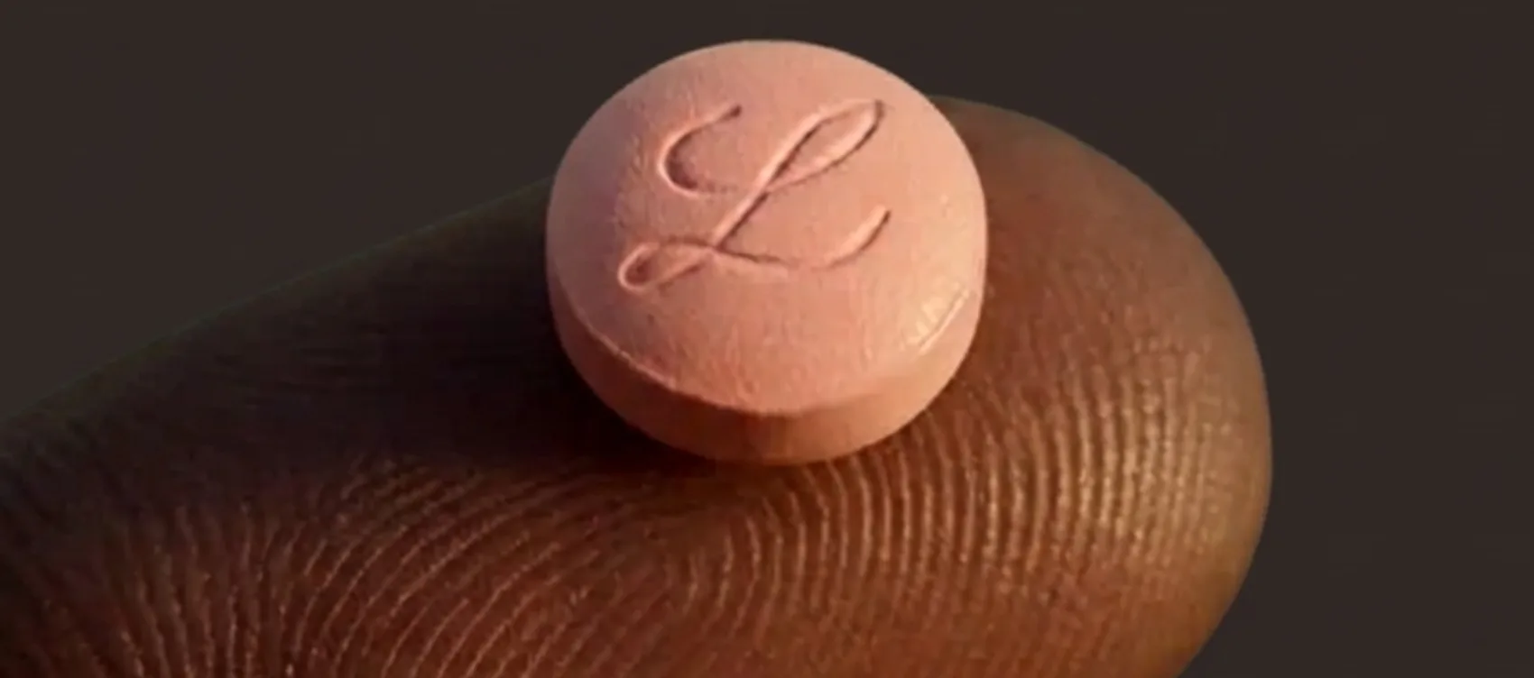 Illustration of an oral GLP-1 tablet on a fingertip, for a Foundayo vs Rybelsus comparison