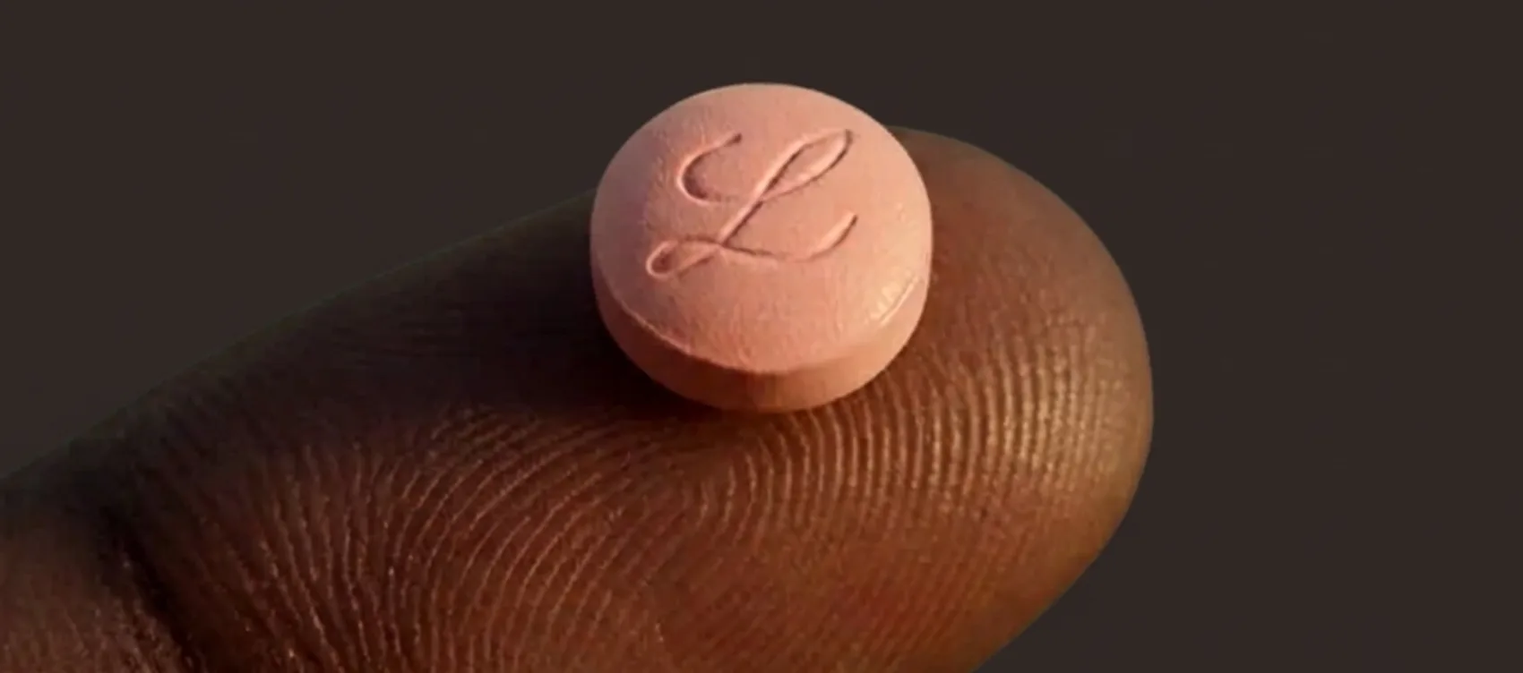 Close-up illustration of an orforglipron tablet held on a fingertip